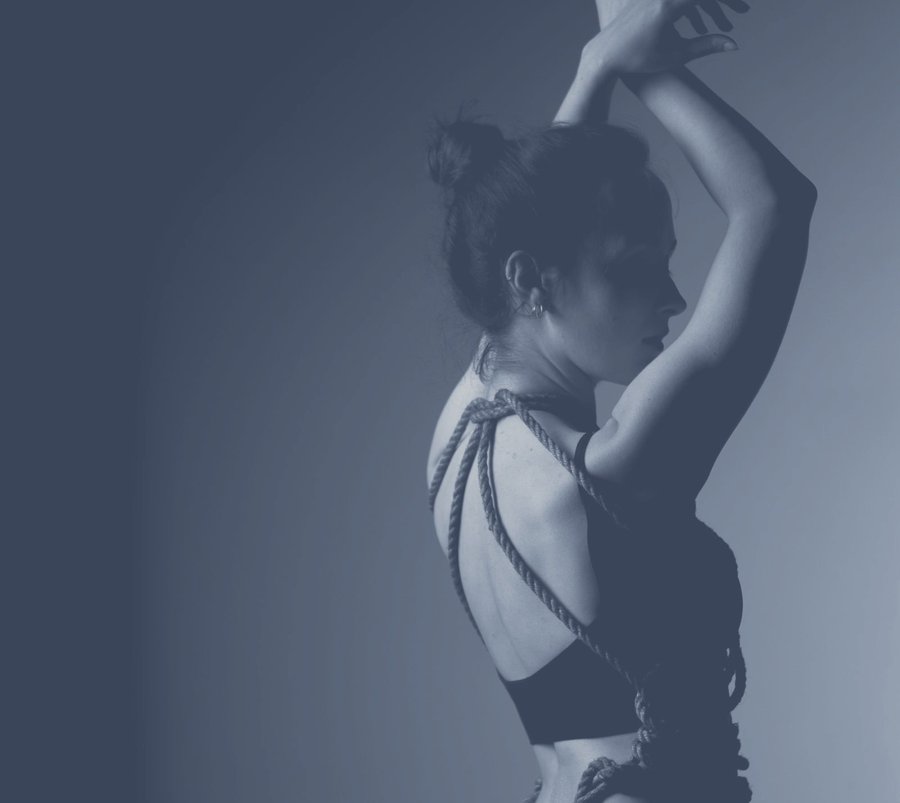 Kunstvolle Silhouette einer Frau mit Shibari-Seilen in gedämpftem Blau