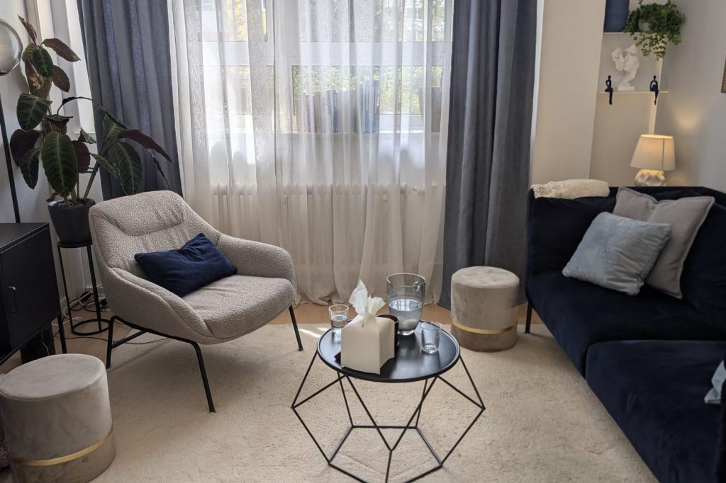 Sessel und Sofa einander zugewandt im Therapieraum der Praxis Patricia Heinis in München